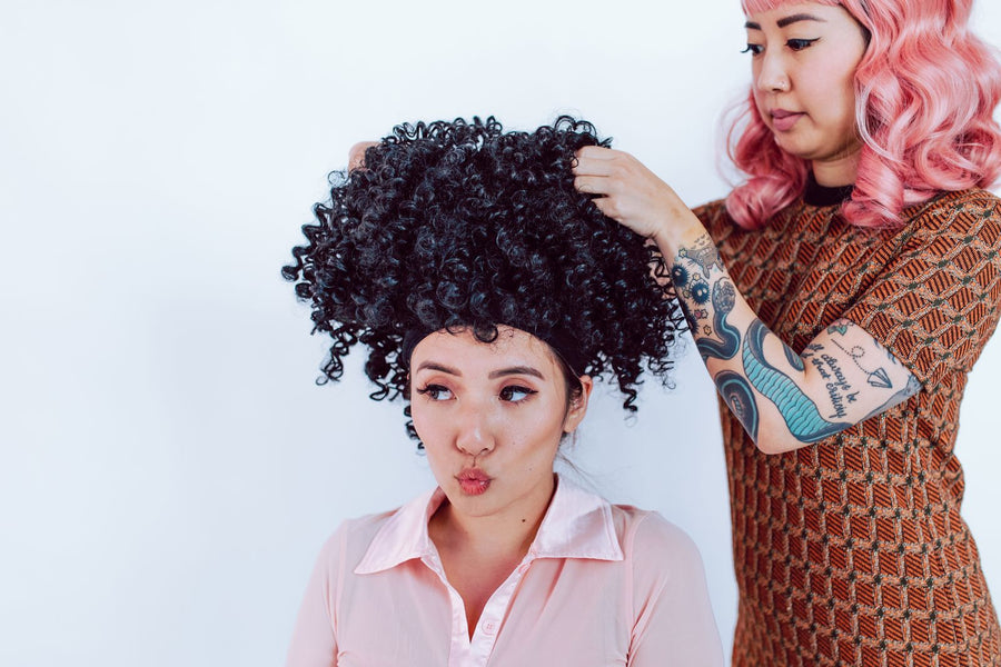 Stylist fitting a curly wig on a client